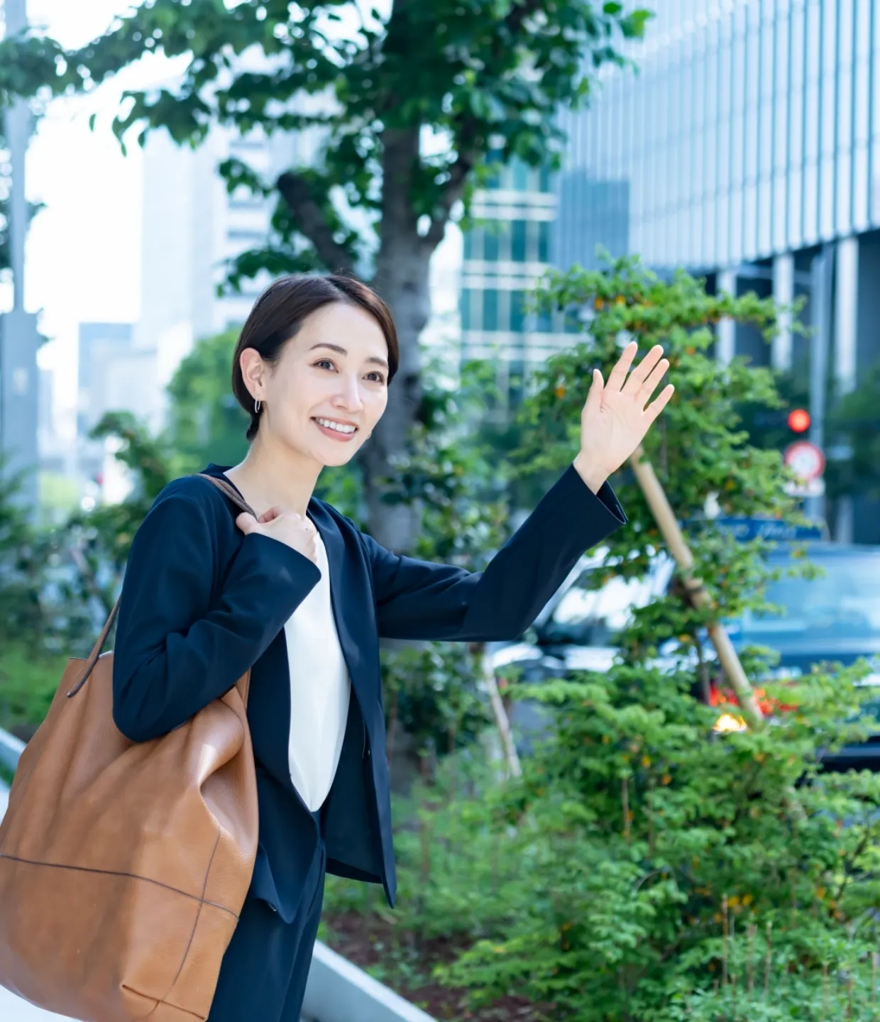 イメージ画像：片手をあげタクシーを停める女性